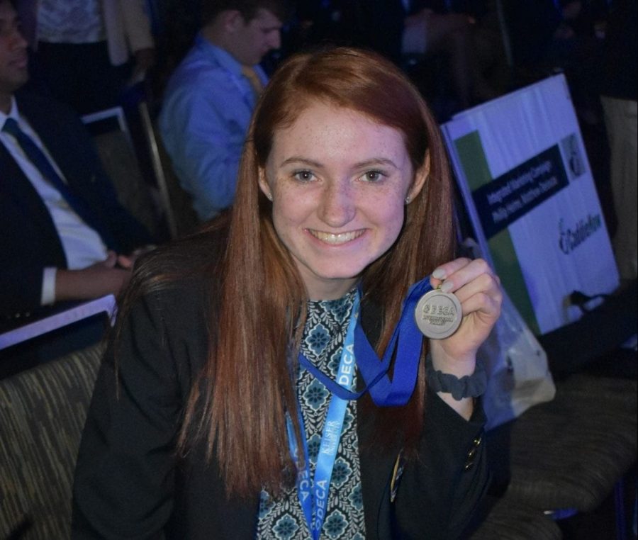 Grace Maloney holds up her International Finalist medal after placing top 10 in her event at ICDC. 