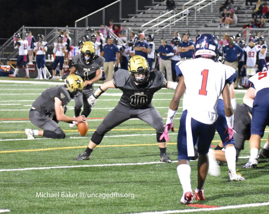 While FHS quarterback Kevin Barton holds the football, kicker Joshua Silva attempts an extra point during the game against the Patriot Pioneers. Photo by Michael Baker III
