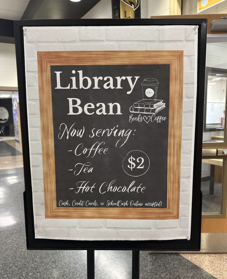 A sign in front of the library informing students about what is offered by the Library Bean. 