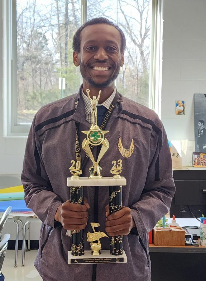 Track and Field head coach Anthony Kitchens holds the boys first place trophy from the Shamrock Invitational hosted by Dominion High School. 