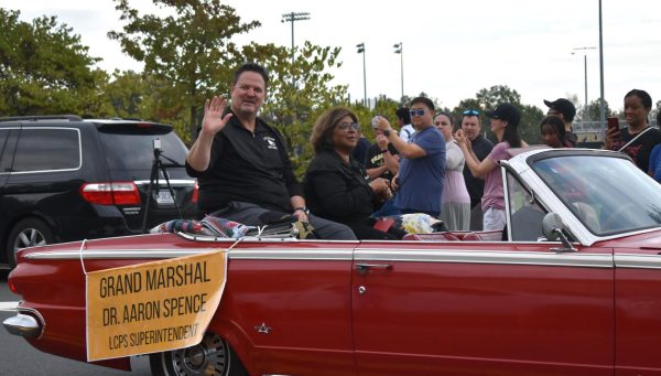 Loudoun Countys new Superintendent Aaron Spence being carried in a red convertible with Principal Neelum Chaudhry through the homecoming parade.  