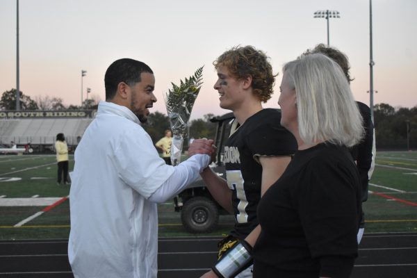 FHS football senior Jacob Lewis receives flowers from FHS football head coach Marcus Mayo at the Fall Sports Senior Night. Photo by Amelia Lee