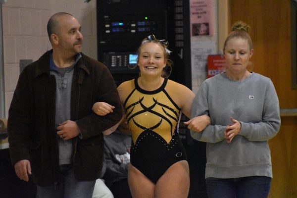 Senior Riley Mullins walks with her parents during the Freedom Gymnastics 2024 Senior Night.