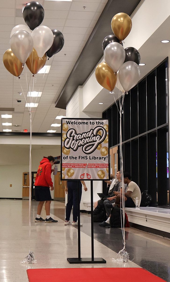 Students and parents are welcomed by a red carpet and black, white, and gold balloons. 