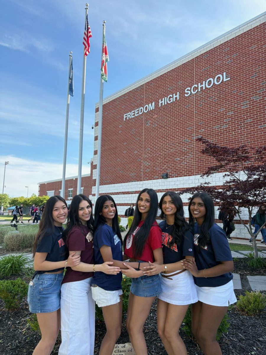 Seniors Kristine Le, Labibah Baba, Taanvi Annapureddy, Riva Shah, and Amy Cherian (left to right) posing in front of Freedom High School with their college T-shirts. 